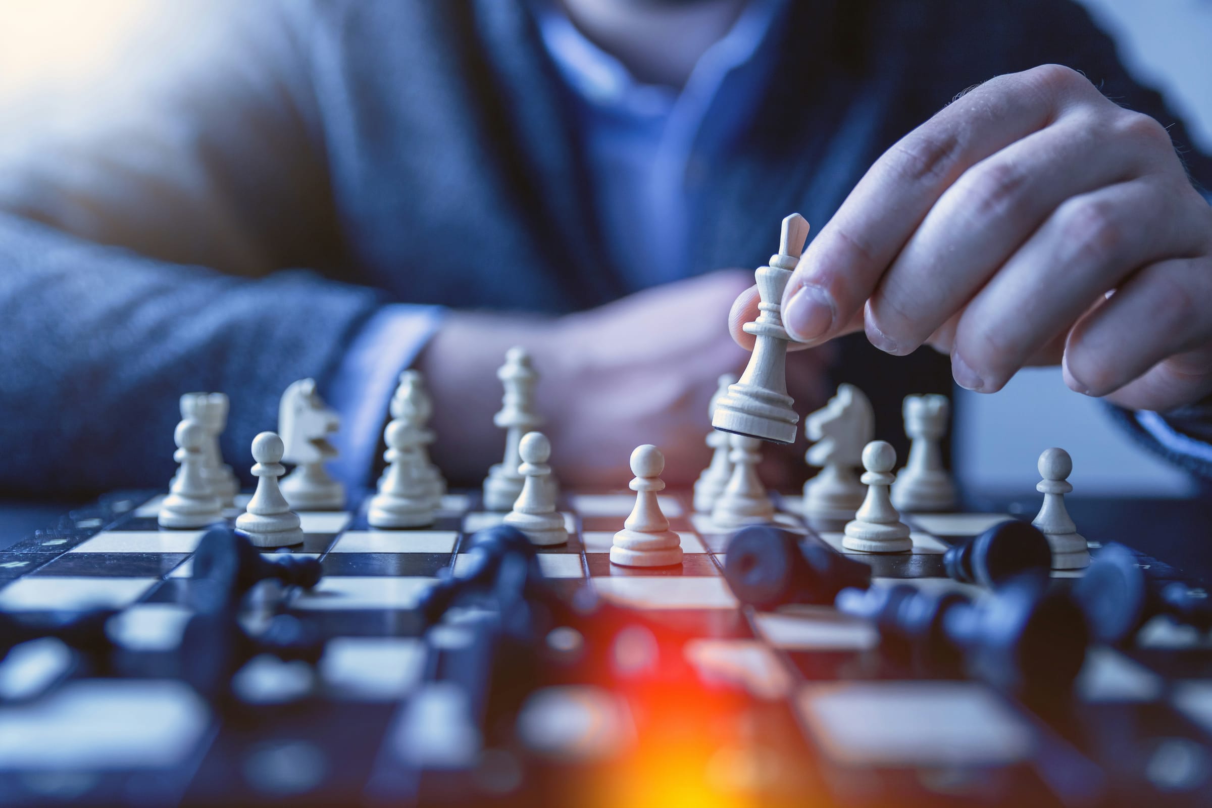 A hand advancing the white king across the board, mid-strategy